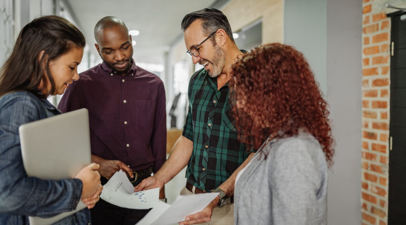 Casual standing business meeting of diverse business team analyzing financial data