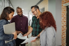 Casual standing business meeting of diverse business team analyzing financial data