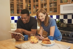 Husband showing his wife a funny news story on his tablet in their kitchen